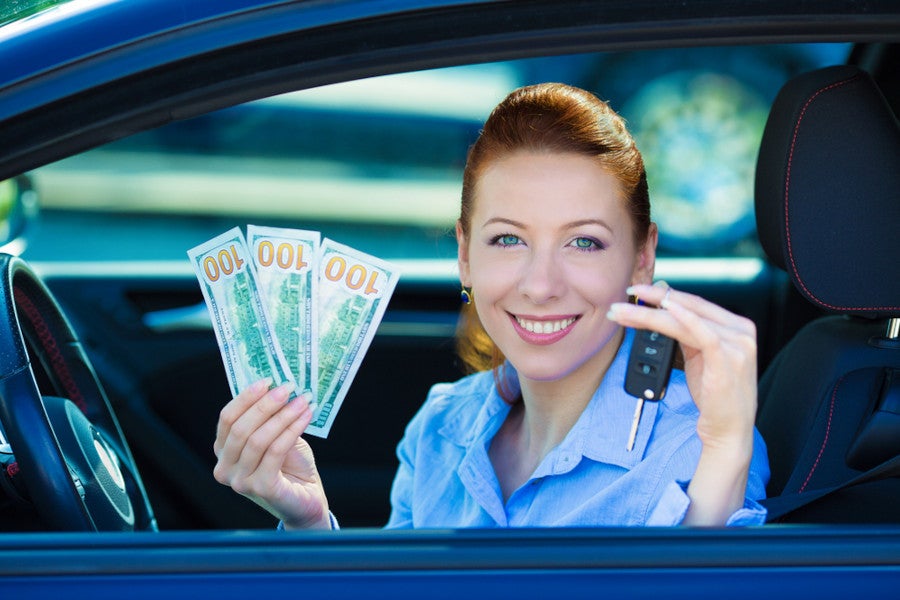 Woman in car holding cash and car keys